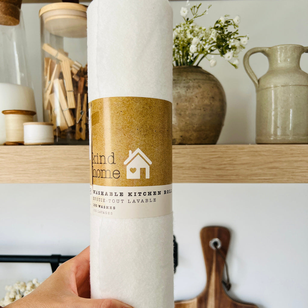 Hand holding a roll of reusable kitchen roll with a rustic shelf in the background